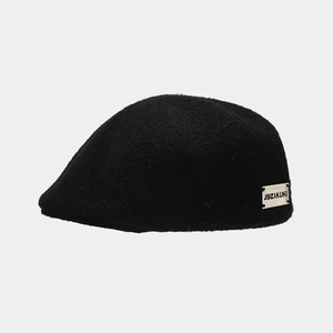 Macro shot of thick black wool beret fabric with white brand logo label detail
