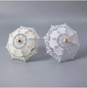Detailed close-up of white and cream lace wedding umbrellas with wooden handles