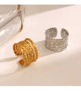 Close-up of gold and silver layered rings with floral relief and beaded texture