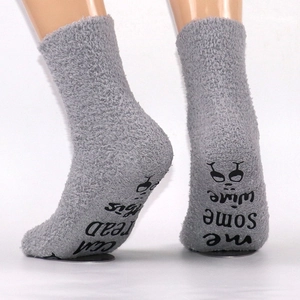 Close-up of non-slip letters and wine icons on the bottom of gray coral fleece socks