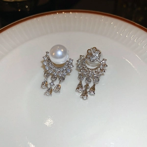 Close-up of pearl tassel earrings with cubic zirconia inlays on a ceramic tray
