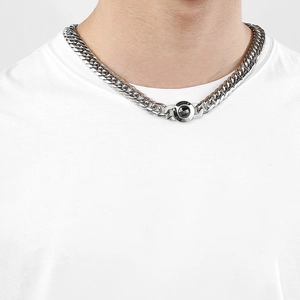 Close-up of polished silver curb chain necklace with unique round clasp on male model