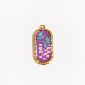 Detail of an oval titanium steel pendant with purple enamel and floral motifs