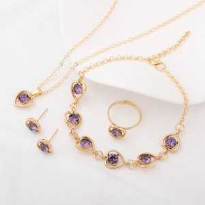 Detail view of a four-piece jewelry set with purple heart crystals in gold settings