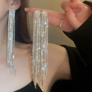 Close-up of sparkling long tassel earrings with oval zircon and silver needle finish