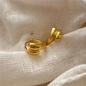 Close-up of golden twisted rope hoop earrings on a textured cream linen background
