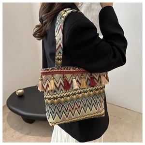 Detail view of woven bohemian tote bag with colorful geometric patterns and tassels