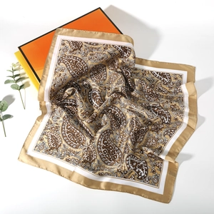 Detailed view of the silk-like square scarf with paisley pattern and orange gift boxes