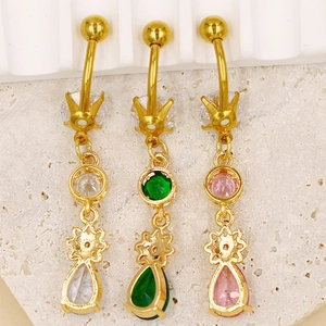 Détail de piercings de nombril dorés avec des zircons en forme de goutte rose et vert