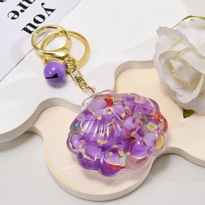 Close-up of purple shell-shaped liquid keychain with bell and golden metal chain