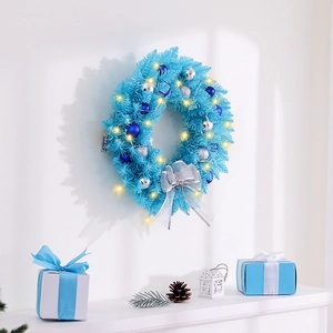 Blue Christmas wreath with silver bow and LED lights hanging on a white wall scenery