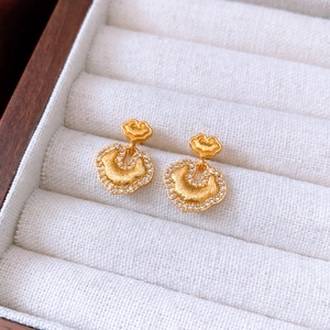 Close-up of 24k gold plated earrings with white zircons in a white velvet jewelry box