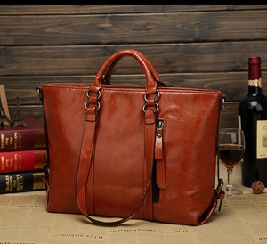 Borsa tote vintage in pelle marrone con anelli metallici su una scrivania di legno