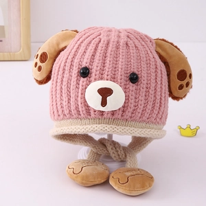 Detailed close-up of pink knit baby hat with dog ears and bone-shaped pom-poms