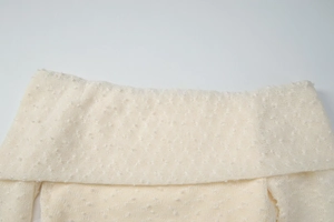 Detail of off-white off-shoulder knit top with unique textured dot knitting technique