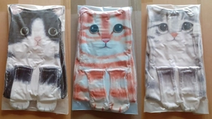 Three cute hanging cat hand towels in black, orange, and grey patterns on wood surface