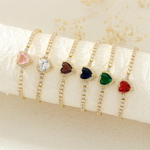 Golden heart bracelets with colorful gems and diamonds arranged on white pillars