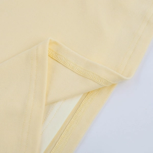 Dettaglio macro del tessuto a maglia giallo con cucitura a doppio ago sull'orlo del vestito