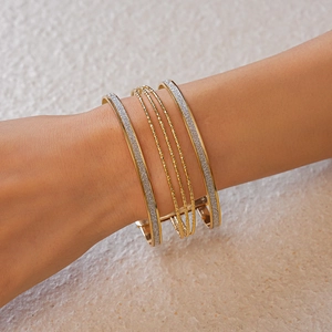 Detail of five-piece gold multilayer geometric cuff set with sparkling textured finish