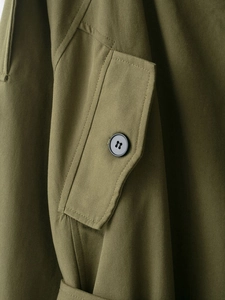 Detailed macro view of army green cotton fabric texture and black button on trench coat