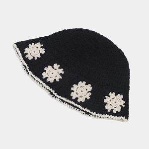 Close-up of black crochet bucket hat with white daisy flowers and wavy scalloped edges