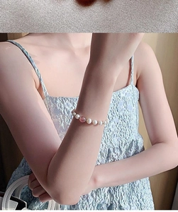 Close-up of elegant pearl bracelet with pink strawberry quartz on woman's wrist