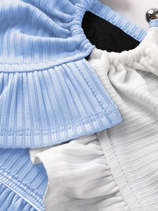 Detailopname van blauw-witte geribbelde Y2K crop top met ruches en een kleine bel