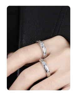 Close-up of couple rings in silver finish with stream texture and zircons on fingers