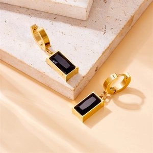 Gold stainless steel hoop earrings with rectangle black gemstone on a stone surface