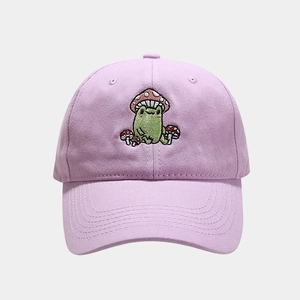 Detailed close-up of cute green frog and mushroom embroidery on lavender baseball cap