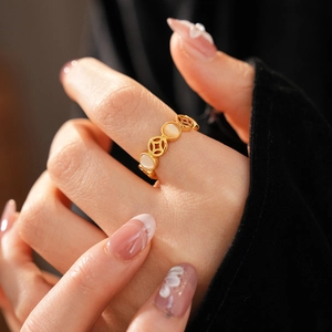 Détail d'une bague dorée vintage avec pièces de monnaie et pierre œil de chat blanc