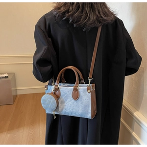 Détail du sac fourre-tout en denim avec poignées en cuir marron et petit charme rond