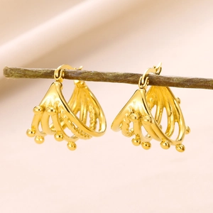 Detailed macro of gold layered fan earrings with beaded edge hanging on a branch