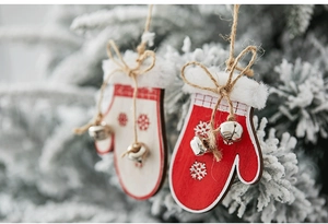 Close-up of wooden Christmas glove ornaments with snowflake patterns and small silver bells
