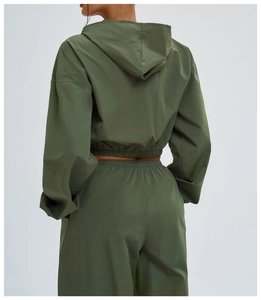 Detail view of a dark green cropped windproof hoodie with elastic hem and back hood