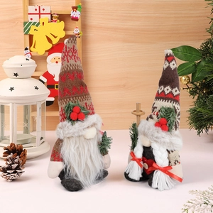 Pair of Christmas gnome plush dolls with knitted hats and pine branch accents on wood