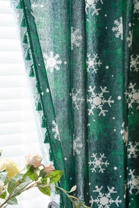 Detail of forest green Christmas curtain featuring white snowflake prints and tassel fringe