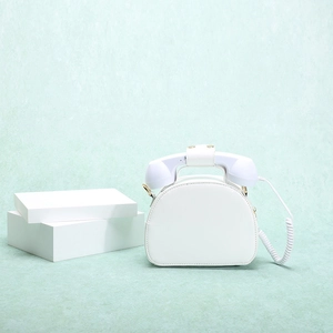 Detailed close-up of a creative white telephone-shaped handbag on a light green background