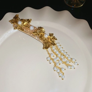 Detail of golden leaf hair clip with pearls and elegant dangling tassel fringe charm