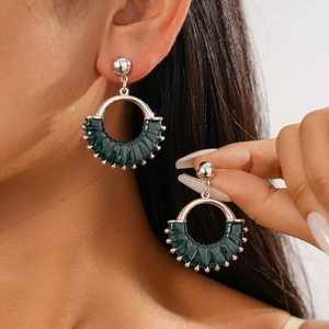 Detail of silver geometric hoop earrings with dark green leather wrap on model