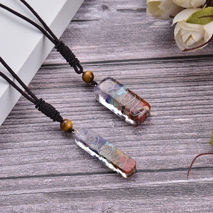 Detail of 7 chakra energy pendant with resin gemstones and copper spiral on wooden table