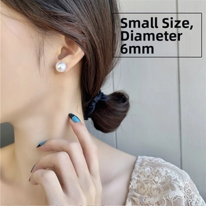 Close-up of small 6mm round pearl stud earrings worn by a model for elegant style