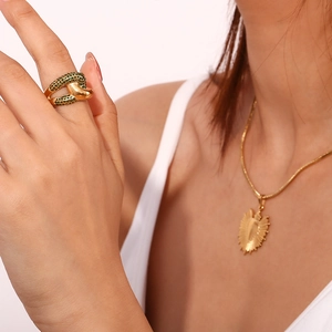 Detailed close-up of 18K gold plated knotted ring with green zircon stones on finger