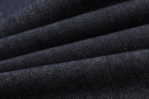 Macro shot of dark indigo denim fabric showing detailed cotton twill texture and weave