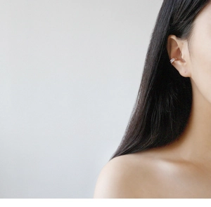 Close-up of minimalist silver triple-line ear cuff worn on a model's upper ear