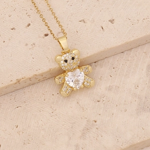 Detailed view of a gold bear pendant with shimmering micro-pave zircons and a heart-shaped stone