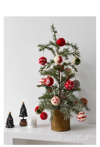 Detail of wool felt Christmas balls with snowflake patterns hanging on a small tree