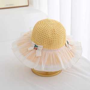 Detail of kids straw sun hat with white lace brim and cute cherry bow ornament
