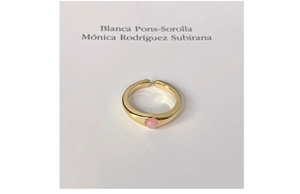 Macro shot of a minimalist gold-plated open ring featuring a round pink gemstone detail