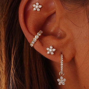 Detailed view of gold flower earrings set with clear zircon stones on a model ear